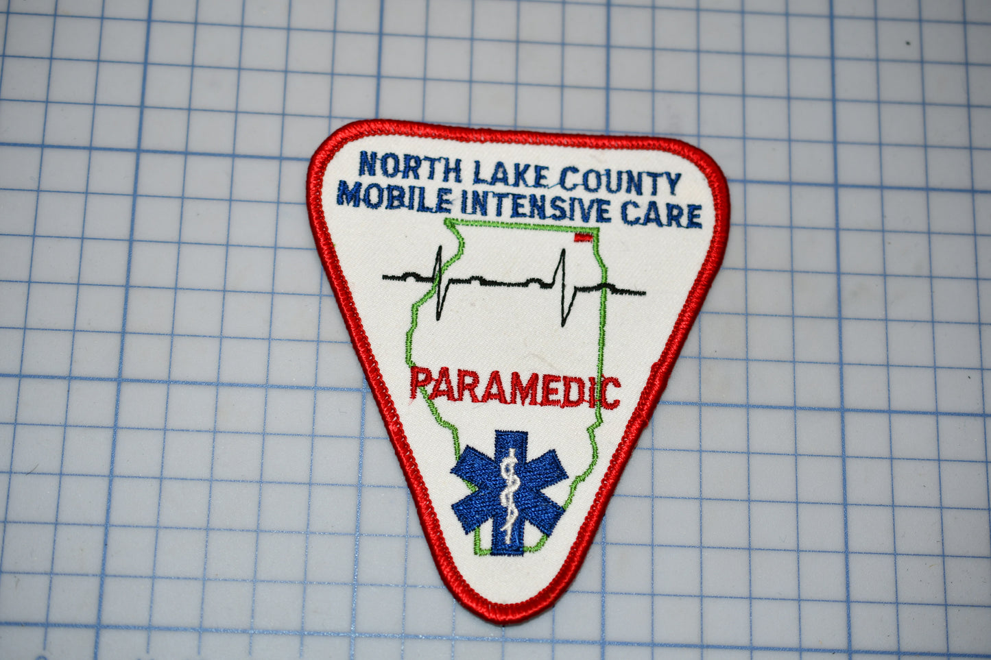 A patch with the text "NORTH LAKE COUNTY PARAMEDIC" and a medical symbol, indicating that it is a patch from the North Lake County Paramedic Service.