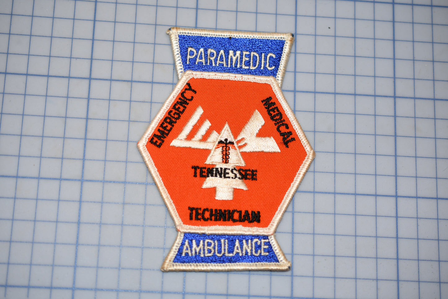 a patch with the words "PARAMEDIC", "EMERGENCY", "TENNESSEE", "TECHNICAL", and "AMBULANCE" printed on it, along with a medical symbol.