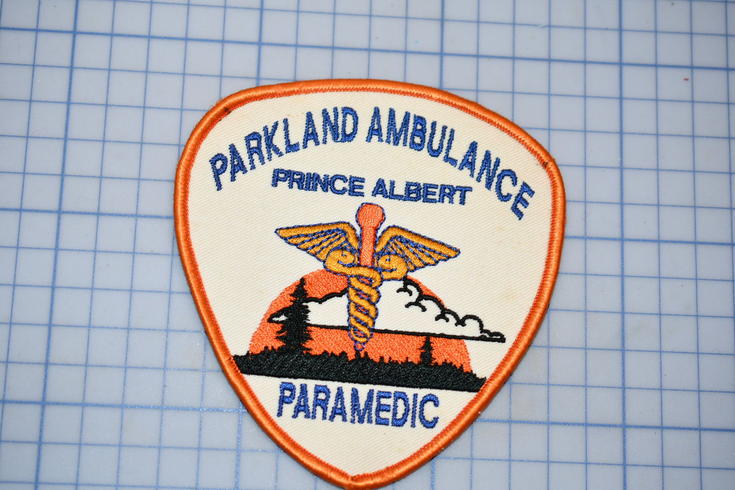 A badge or patch with the text "Parkland Ambulance" and "Prince Albert Paramedic" printed on it, along with an image of a medical symbol.