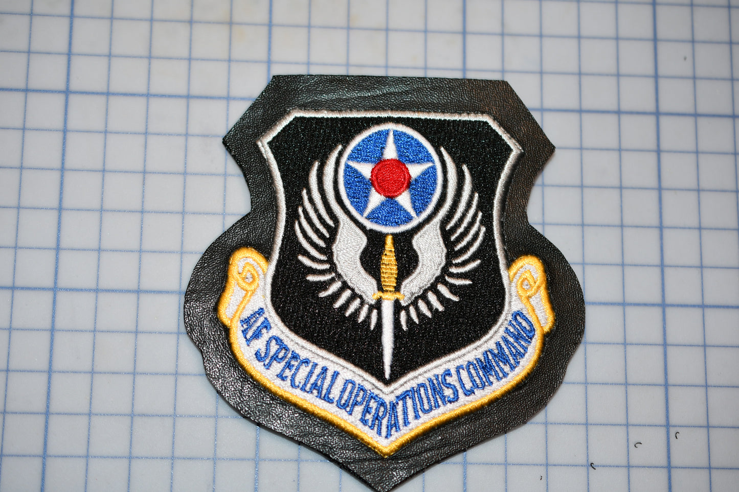 a black and gold emblem with a red star and a blue and white shield, which appears to be a military insignia.