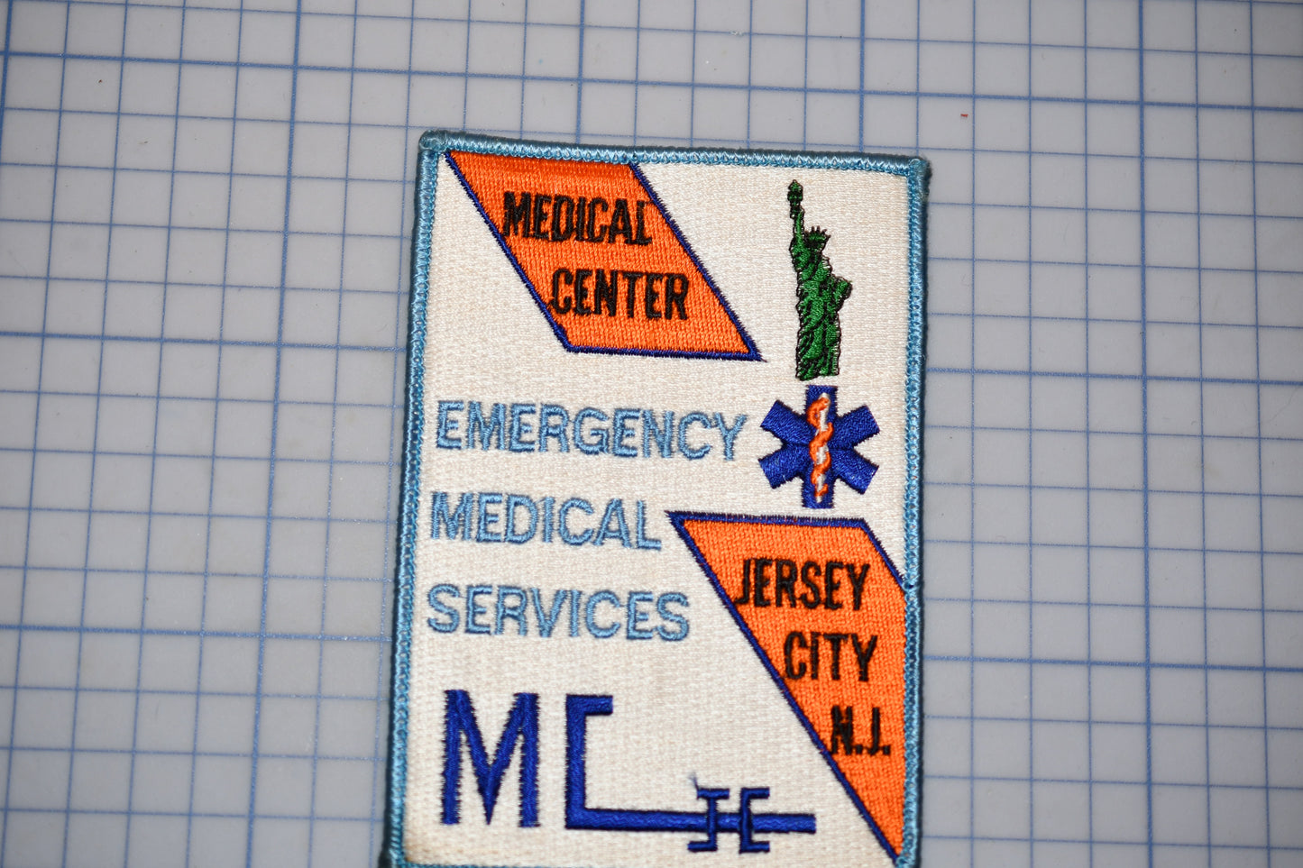 a patch with text and a symbol, including the words "MEDICAL CENTER", "EMERGENCY MEDICAL SERVICES", and "JERSEY CITY N.J."