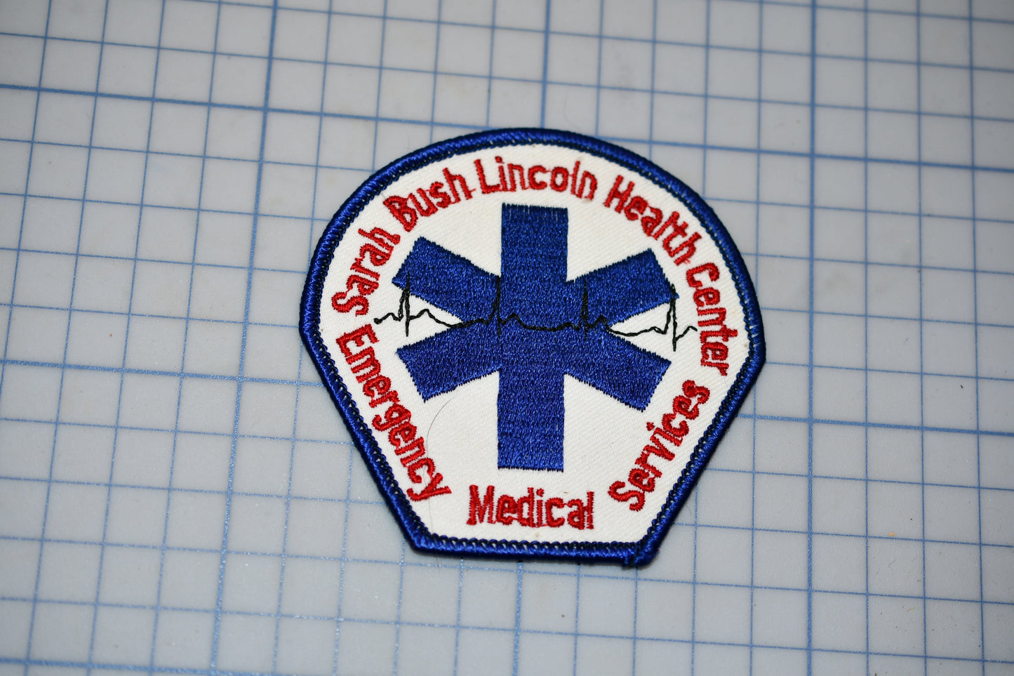a patch with a blue cross symbol and text surrounding it, which appears to be a medical or emergency service patch.