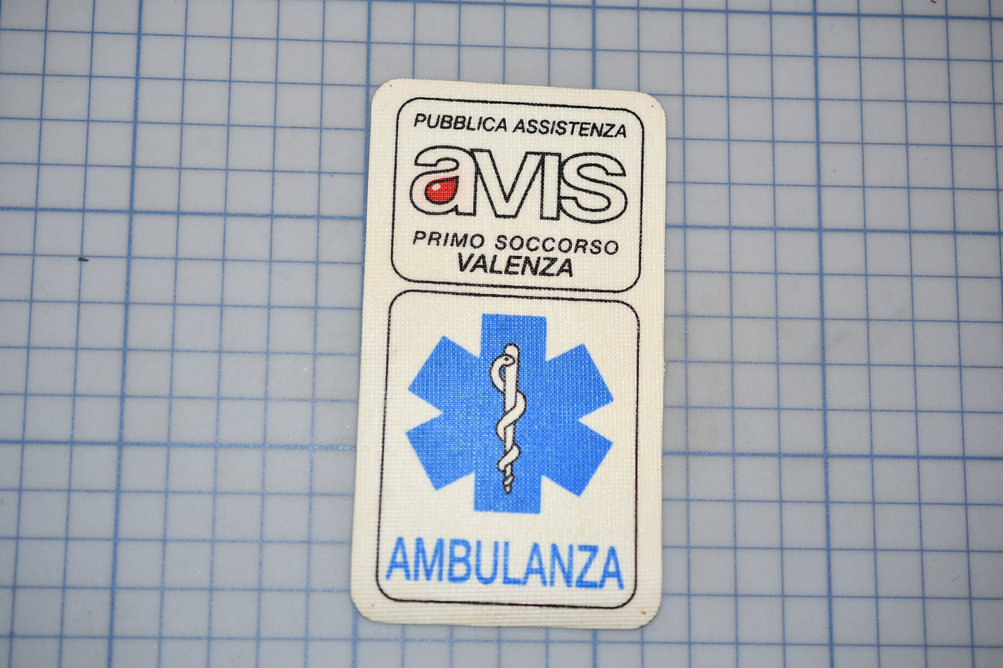 a white patch with text and a medical symbol, placed on a blue grid background.