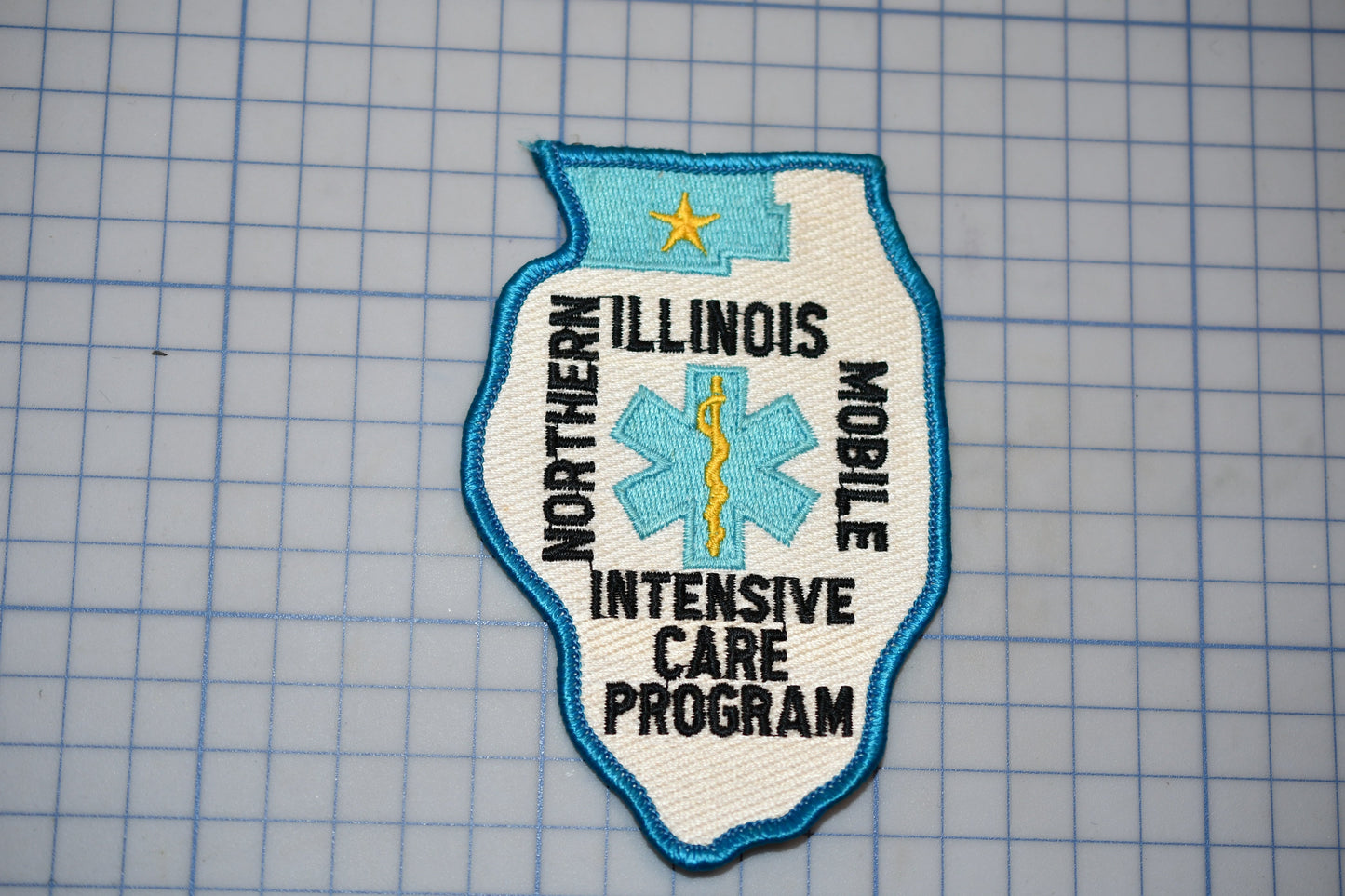 A patch with the text "NORTHERN ILLINOIS MOBILE INTENSIVE CARE PROGRAM" and a medical symbol, likely representing a healthcare program or organization.
