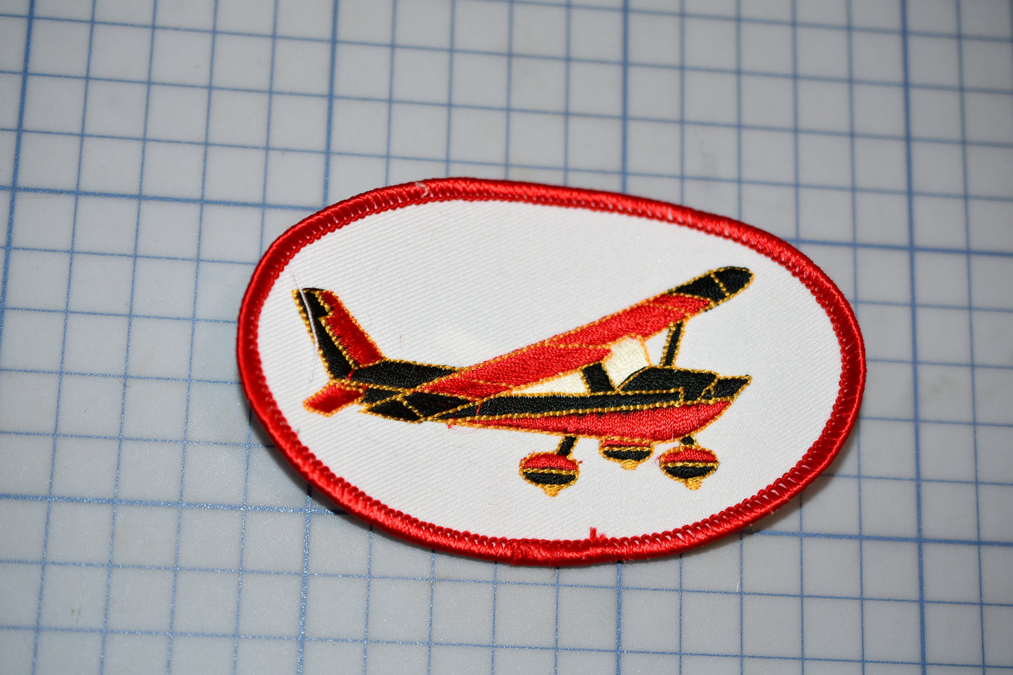 a red and black airplane on a white patch