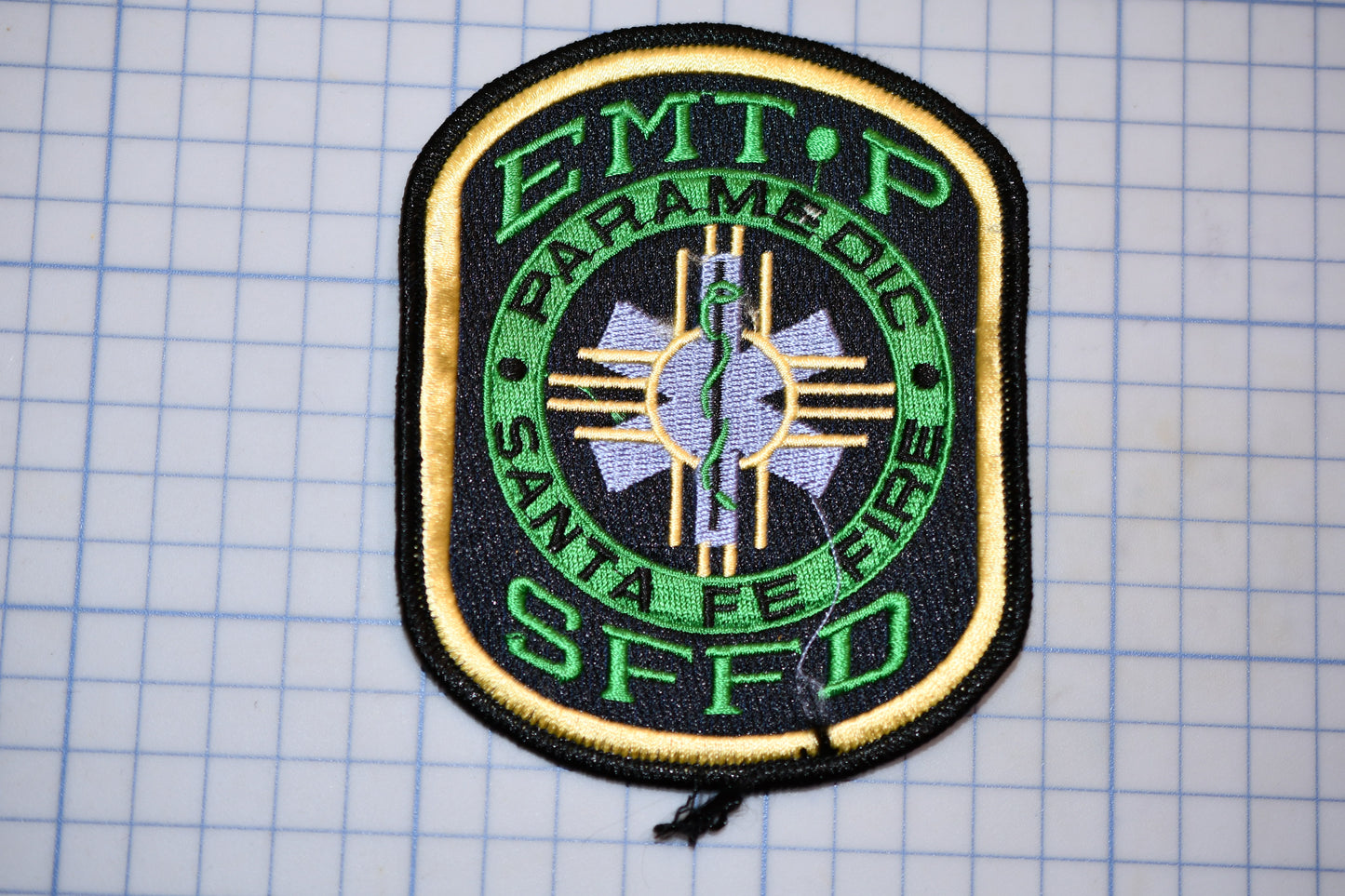 a badge with the text "EMT/P PARAMEDIC SANTA FE FIRE SFFD" on it, which is a badge of the San Francisco Fire Department.