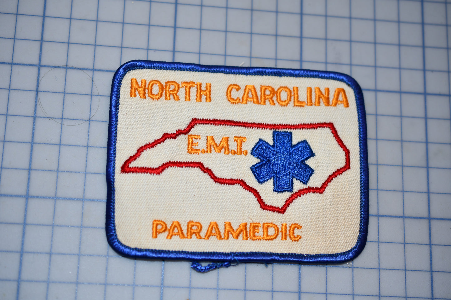 a patch with the text "NORTH CAROLINA EMT PARAMEDIC" and a blue star-shaped symbol, representing the emergency medical services of North Carolina.