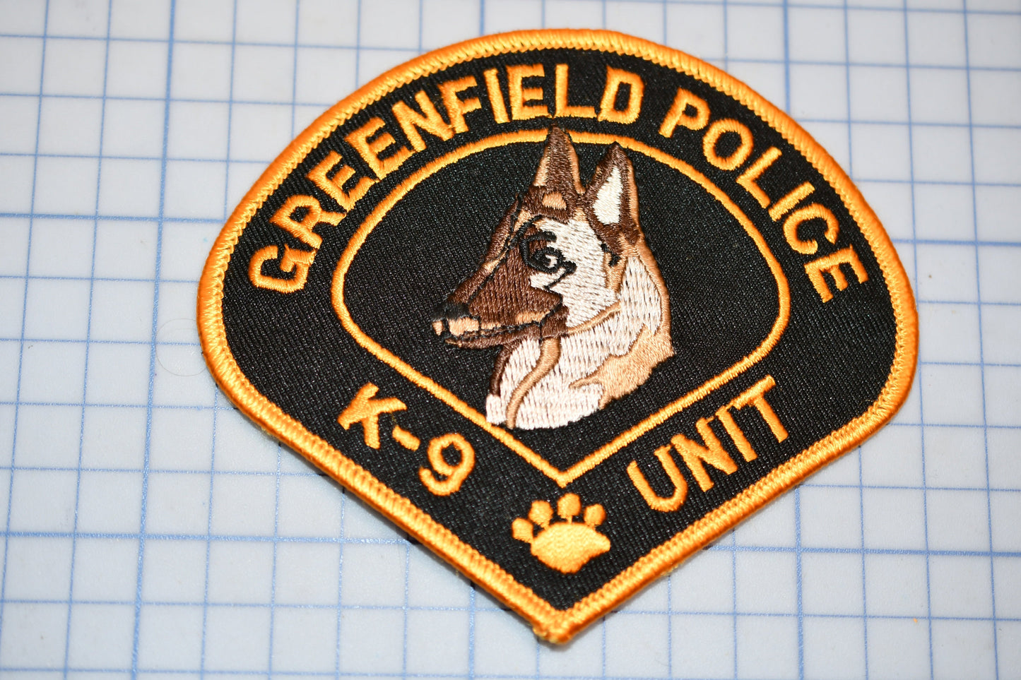 A patch with the text "GREENFIELD POLICE K-9 UNIT" and an embroidered image of a German Shepherd dog.