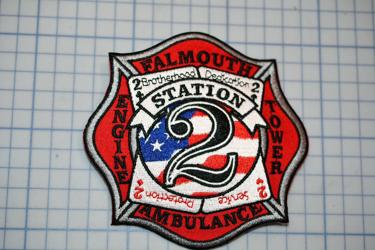 a fire department patch with the words "Falmouth Station 2 Ambulance" and an American flag design.