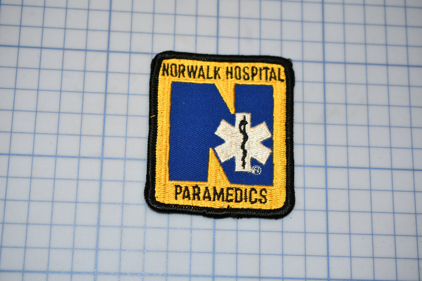 A patch with the text "NORWALK HOSPITAL PARAMEDICS" and a medical symbol, likely representing the emergency medical services of the Norwalk Hospital.