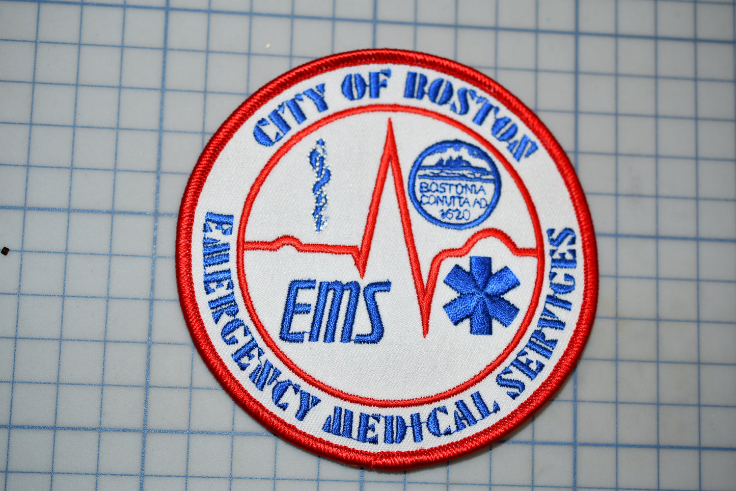 a circular patch with the text "CITY OF BOSTON EMT" and "EMERGENCY MEDICAL SERVICES" written on it.