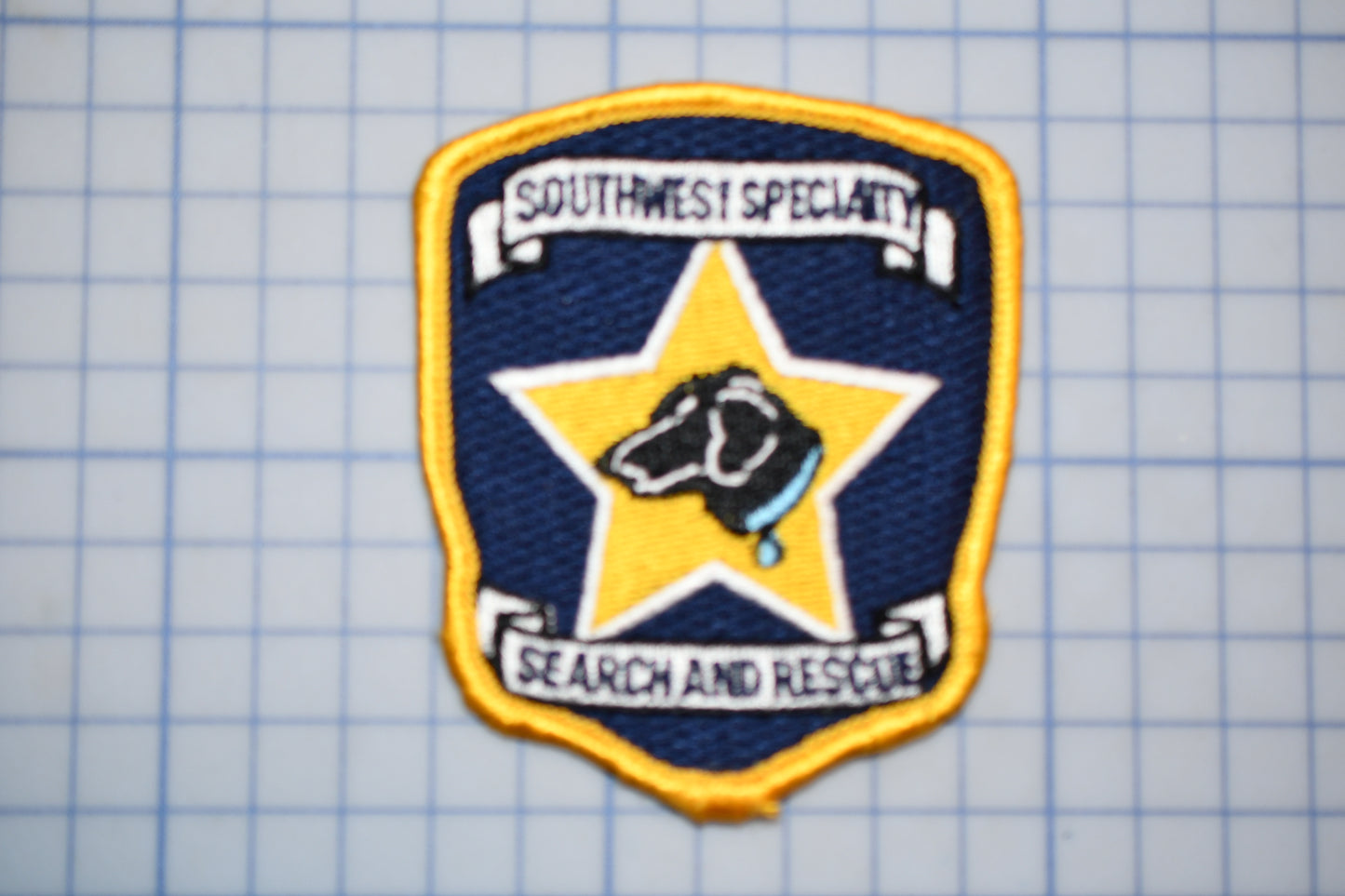 a badge with a dog on it, which is part of the Southwest Specialty Search and Rescue team.