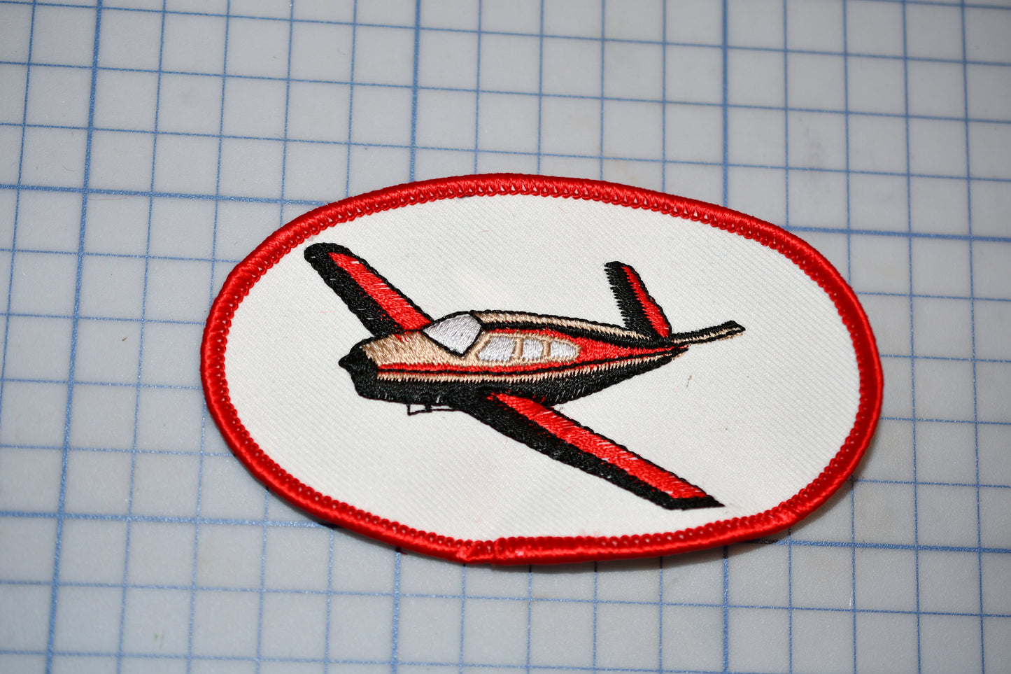 a red and white patch with a small plane on it