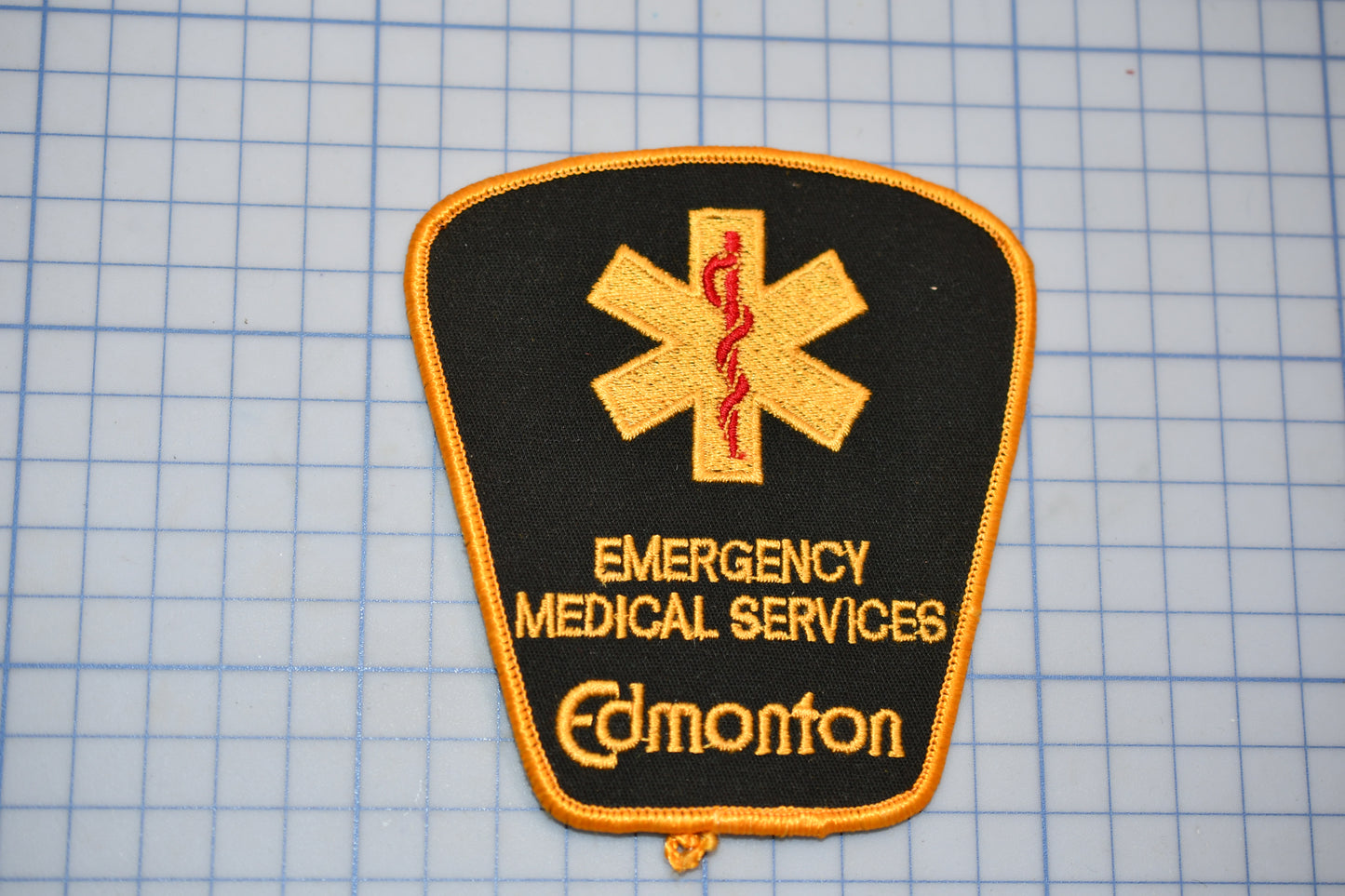 a patch with the text "EMERGENCY MEDICAL SERVICES" and "Edmonton" printed on it, along with a medical symbol.