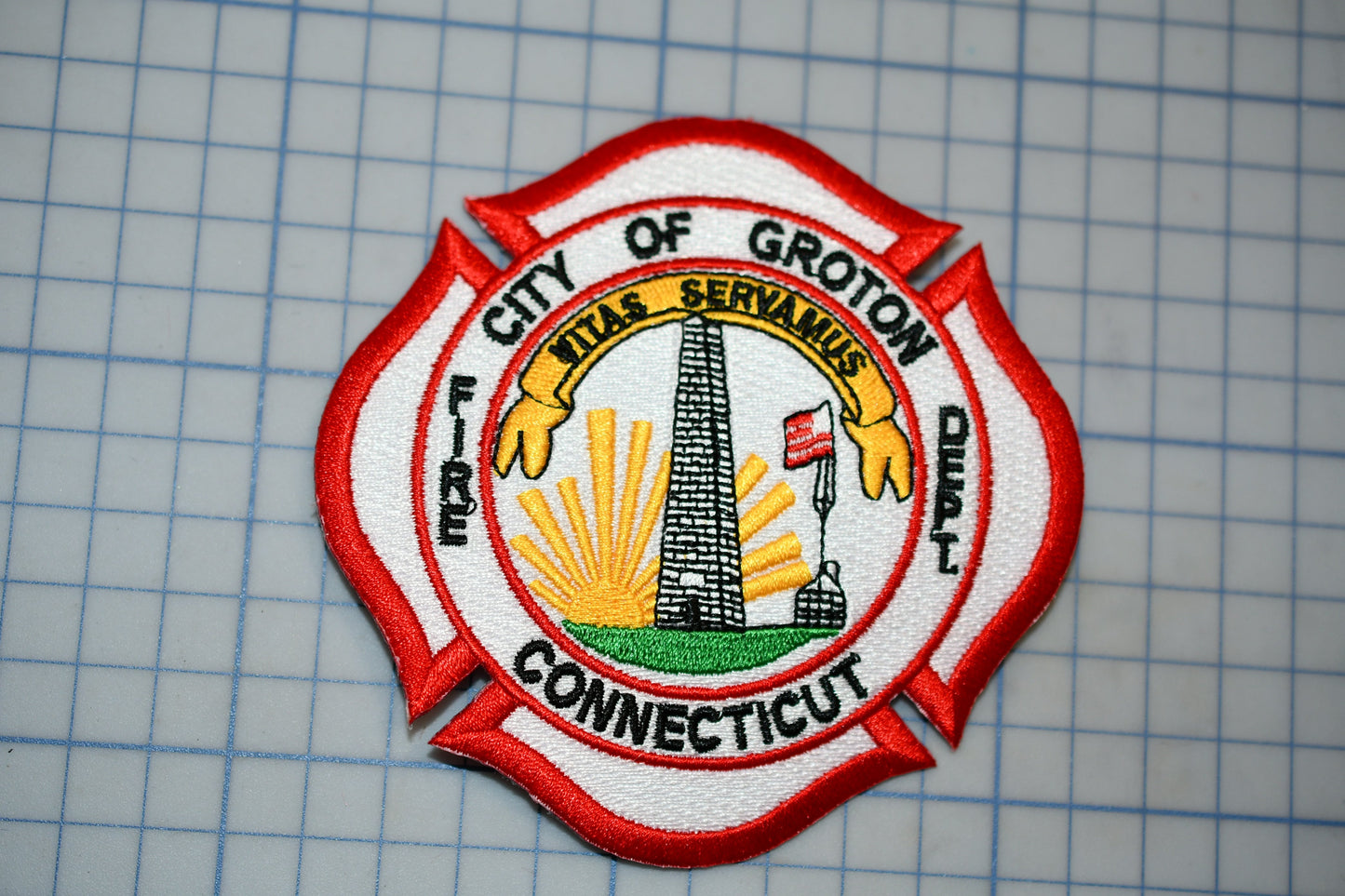 a fire department emblem with a red and white color scheme, including a sunburst design and a flag.