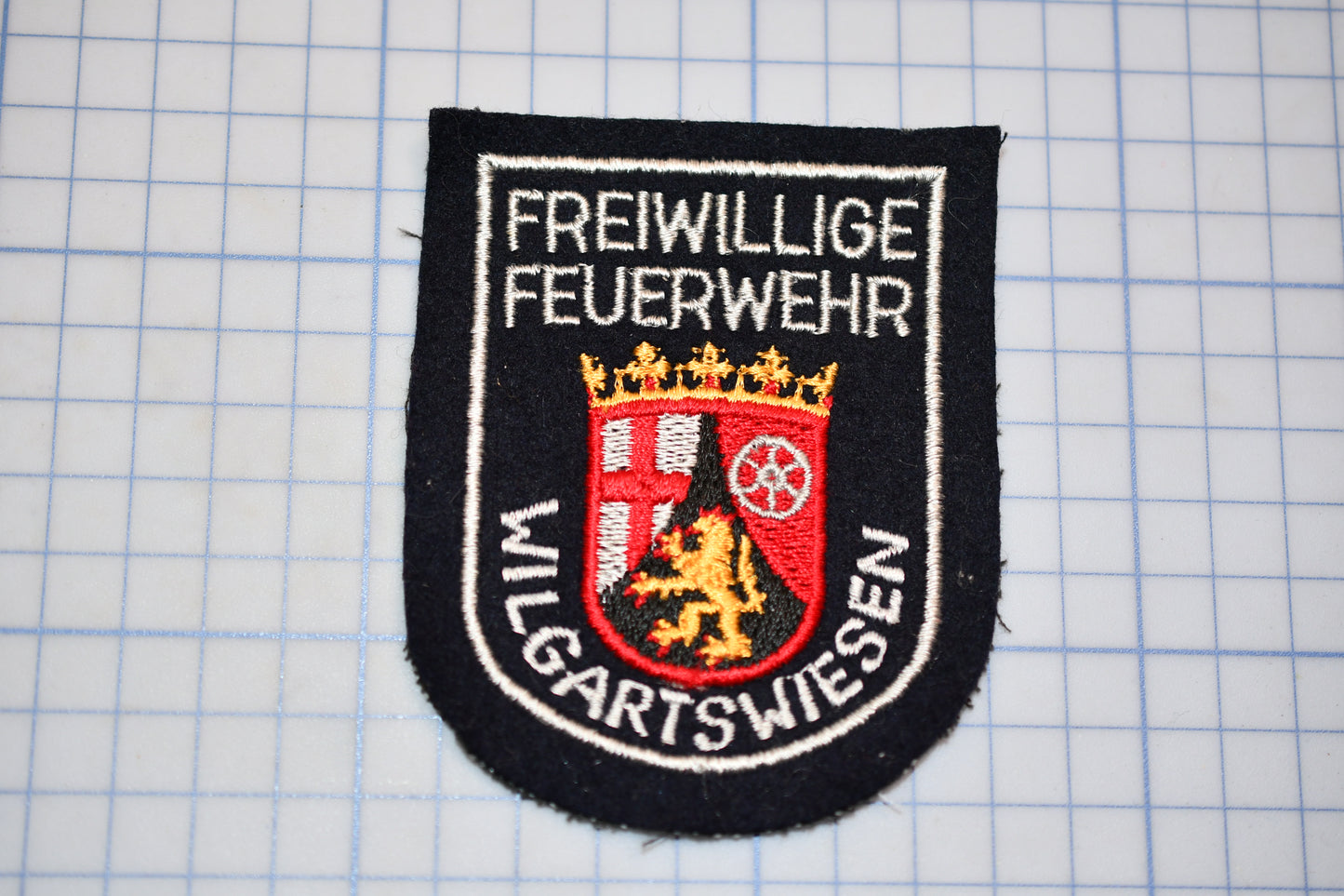a black and white patch with text and a coat of arms.