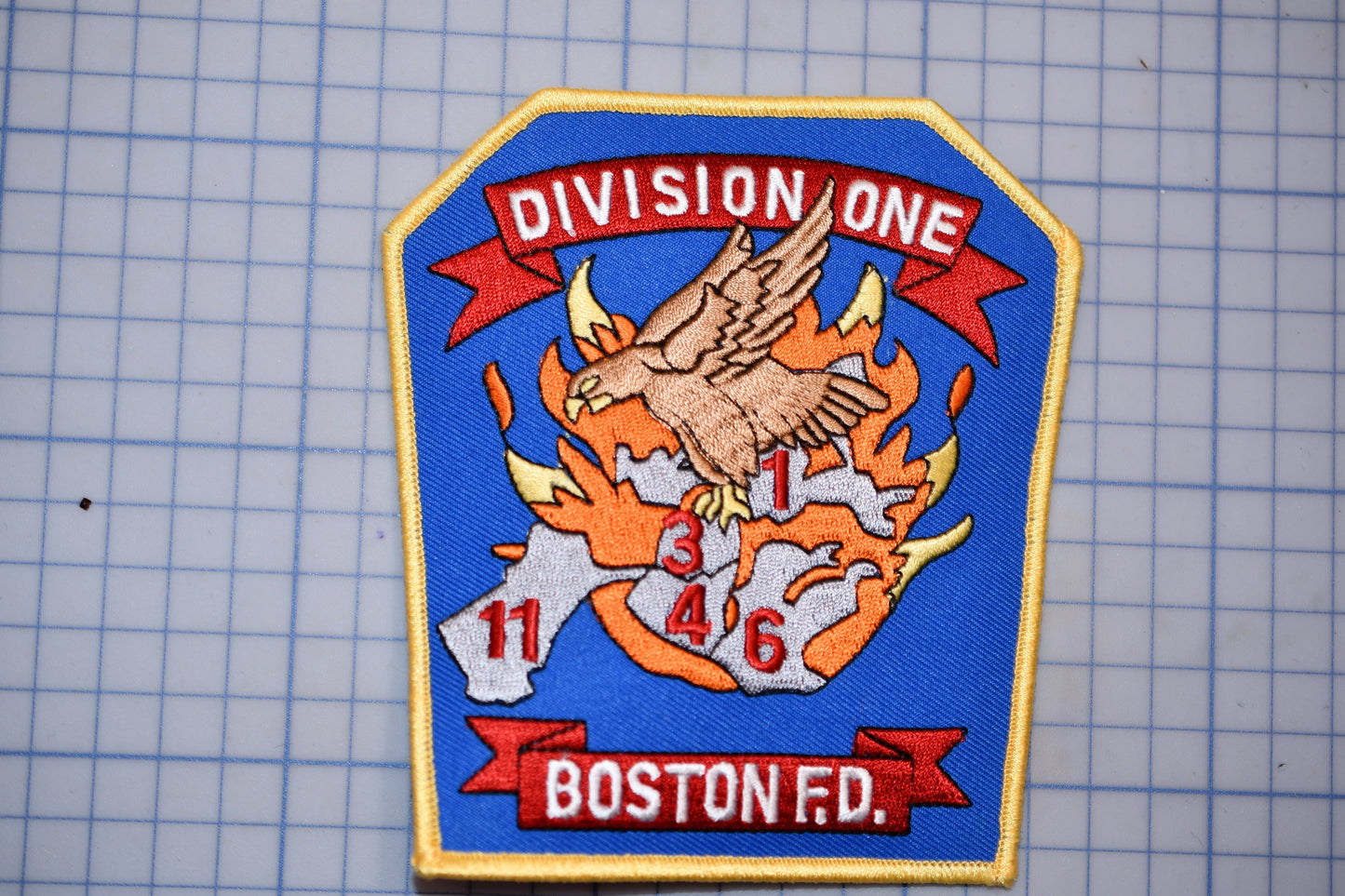 a fire department patch with a bird, flames, and the text "Division One" and "Boston Fire".
