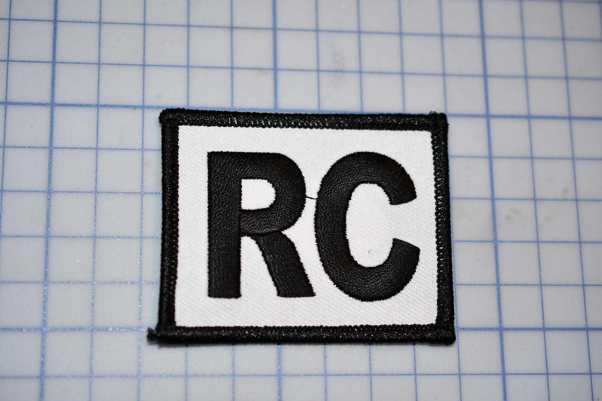 a black and white patch with the letter rc on it