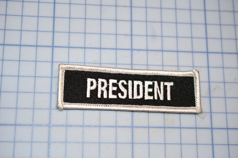 a black and white patch with the word president on it