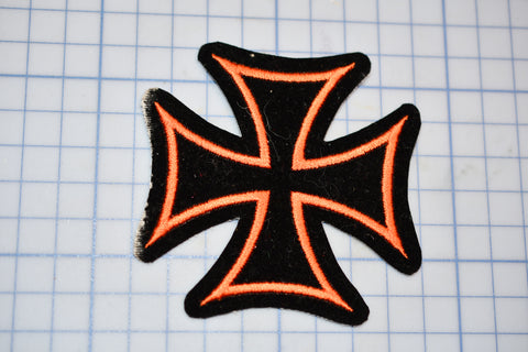 a black and orange iron cross patch sitting on a piece of paper