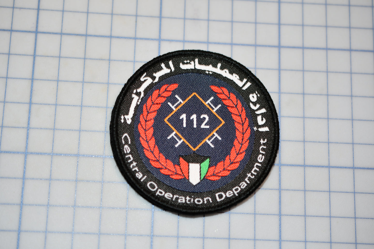 a circular patch with a logo and text, placed on a grid background.