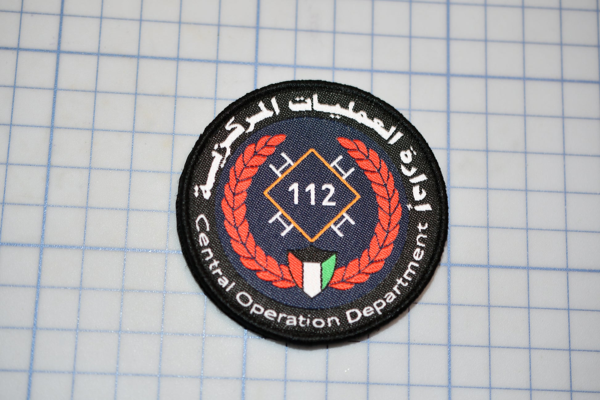 a circular patch with a logo and text, placed on a grid background.