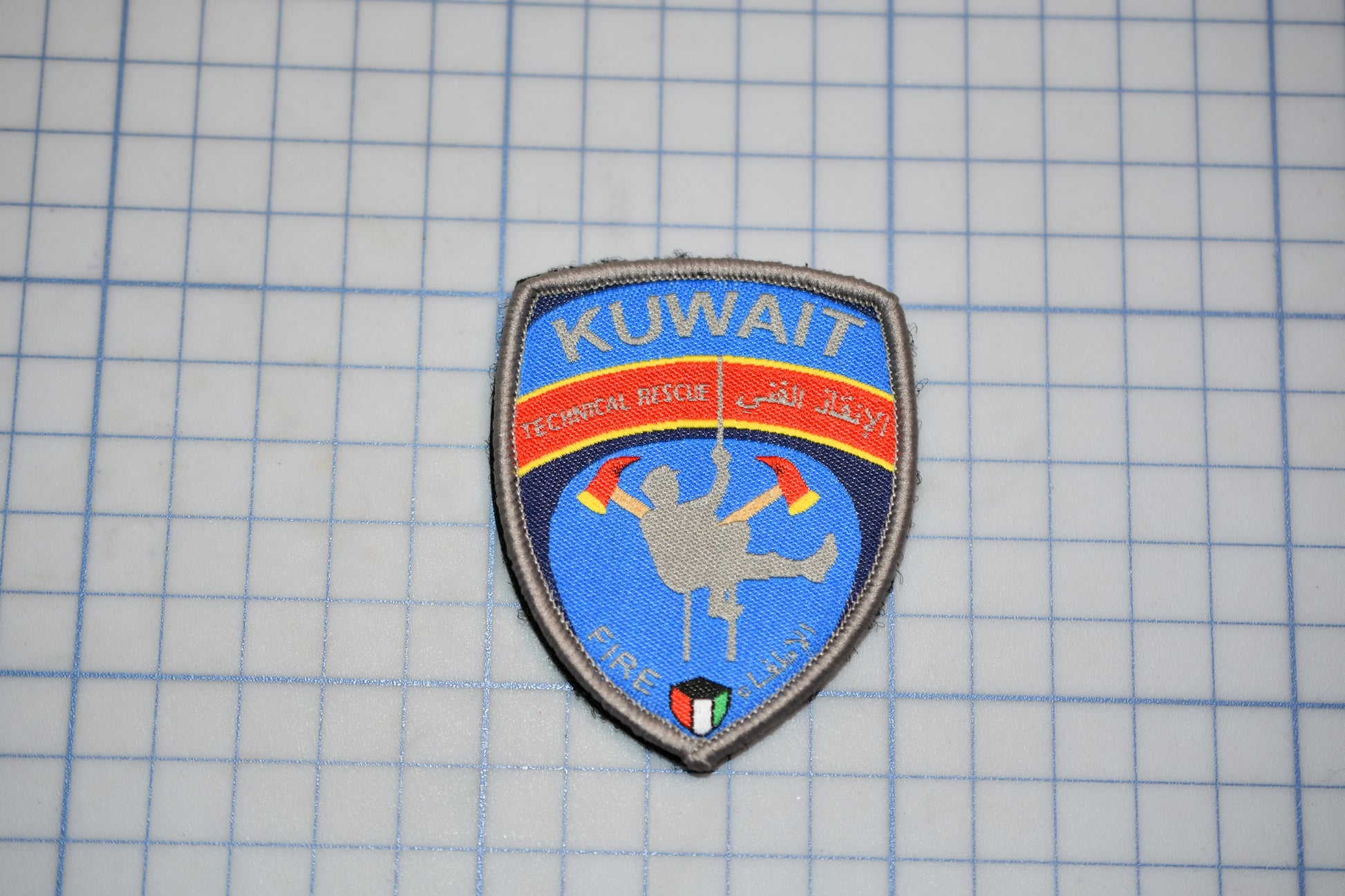 a blue and red patch with a graphic design, placed on a grid background.