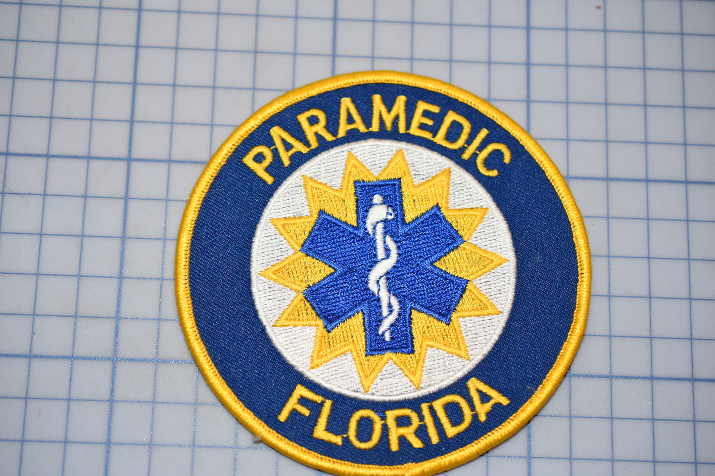 a circular patch with the text "PARAMEDIC FLORIDA" and a medical symbol, likely representing a medical emergency response team or organization.