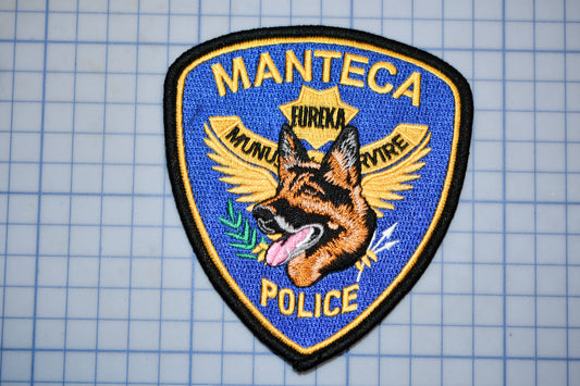 A police patch with a dog's head and wings, along with the text "MANTECA POLICE".