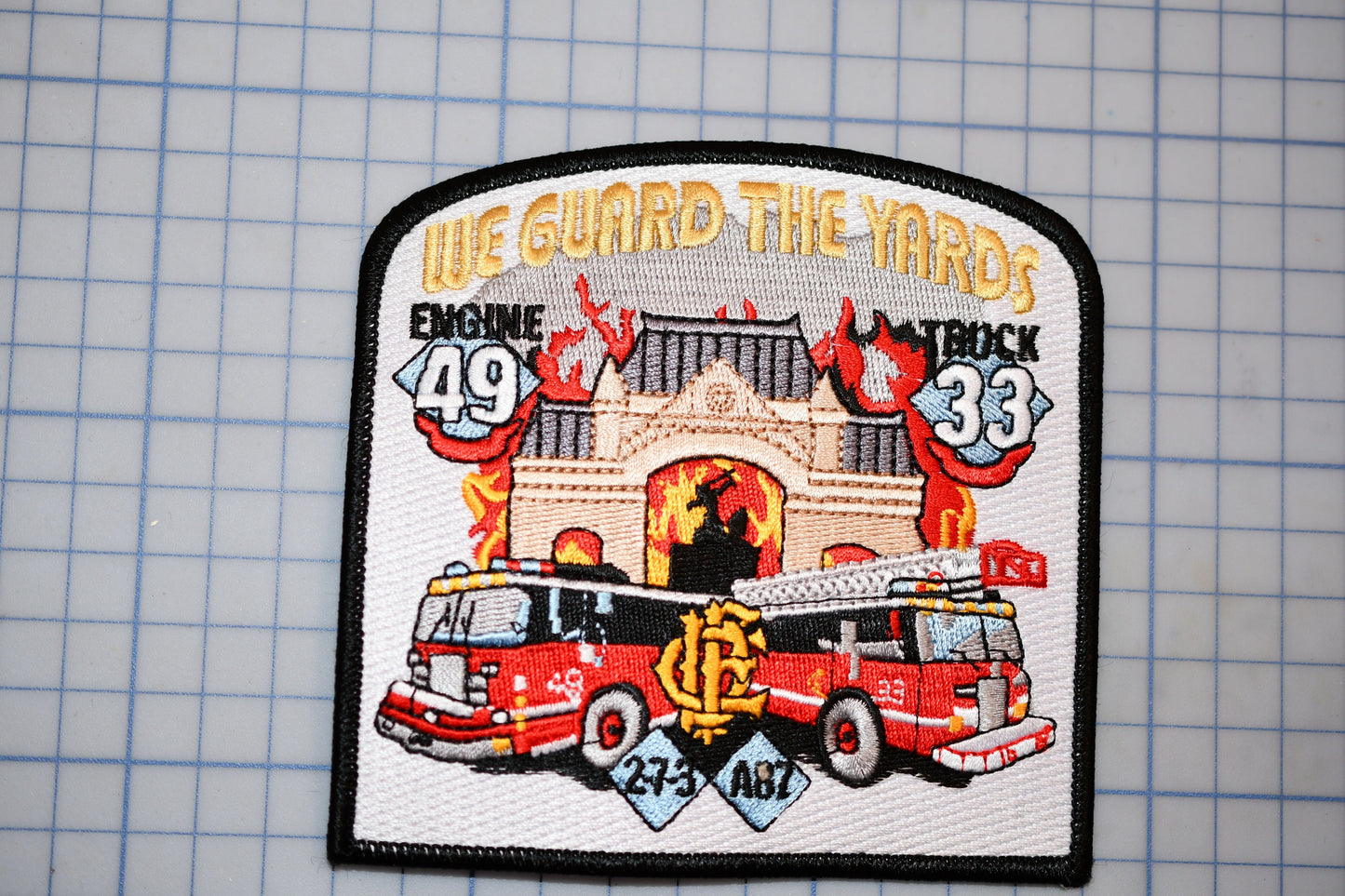 a patch with a fire truck and a building with flames, along with the text "We guard the yards" and "Engine 49" and "Fire truck 33".