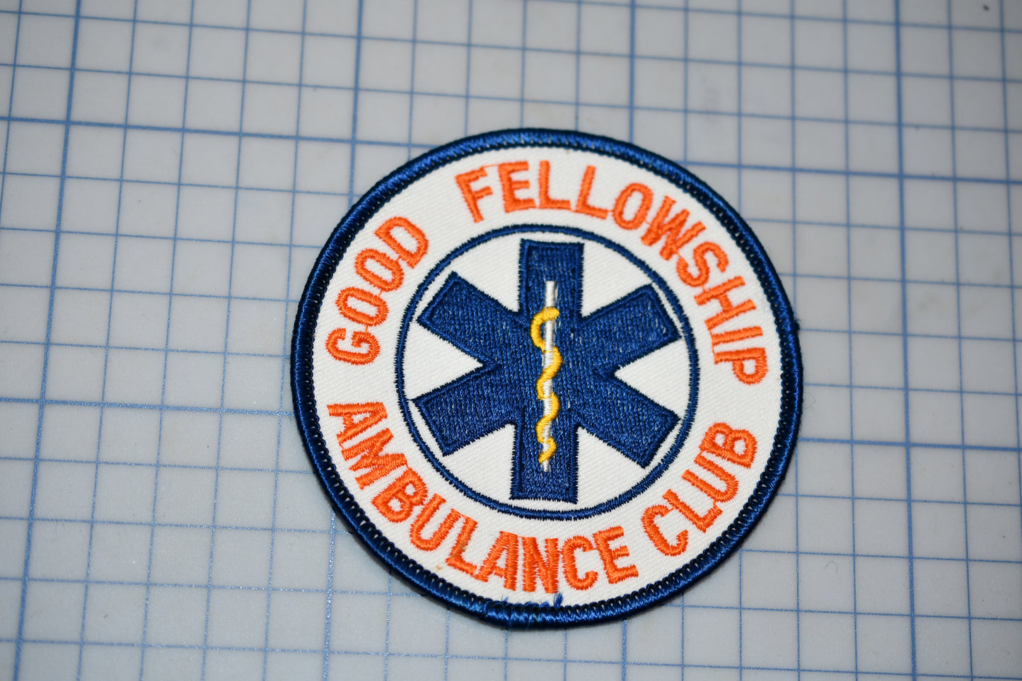 a patch with the text "Good Fellowship Ambulance Club" and a medical symbol, likely representing a medical or emergency services organization.