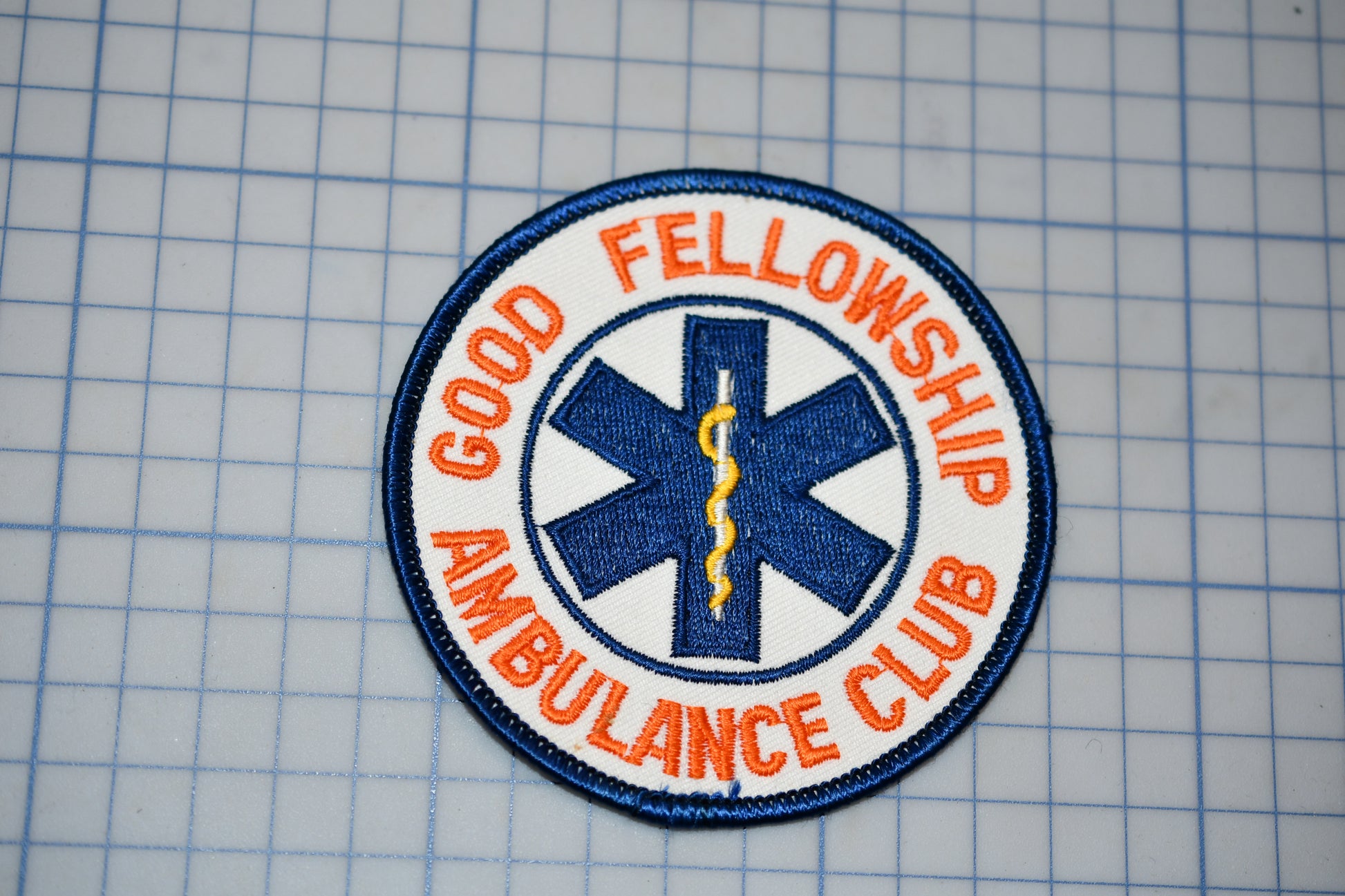 a patch with the text "Good Fellowship Ambulance Club" and a medical symbol, likely representing a medical or emergency services organization.
