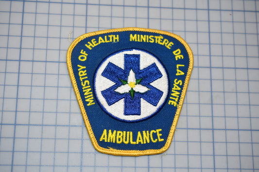 a blue and yellow patch with the text "Ministry of Health Ambulance" and a medical symbol, all set against a grid background.