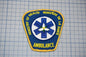 a blue and yellow patch with the text "Ministry of Health Ambulance" and a medical symbol, all set against a grid background.
