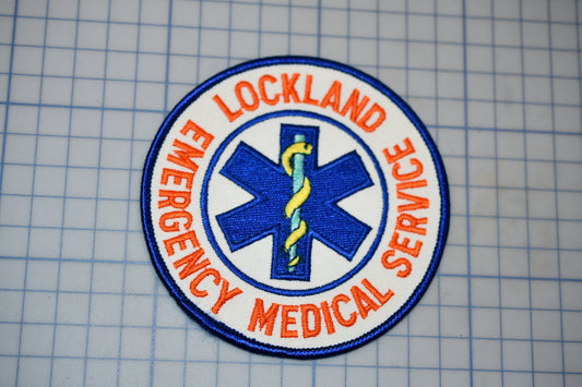 a circular patch with the text "LOCKLAND EMERGENCY MEDICAL SERVICE" and a medical symbol, such as a cross or stethoscope, encircling it.
