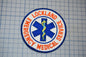 a circular patch with the text "LOCKLAND EMERGENCY MEDICAL SERVICE" and a medical symbol, such as a cross or stethoscope, encircling it.