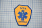 a medical patch with a blue cross symbol and the text "VZA AMSTERDAM" printed on it.