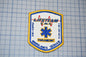 a patch with the word "LIFETIME" written on it, along with a medical symbol. The patch is part of a larger collection of patches, as indicated by the text "LIFETIME EMERGENCY SERVICE" and "PARAMEDIC AMBULANCE SERVICE".