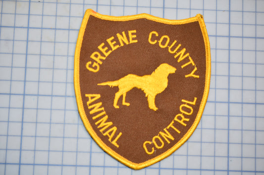 A brown and yellow patch with the text "GREENE COUNTY ANIMAL CONTROL" and a silhouette of a dog.