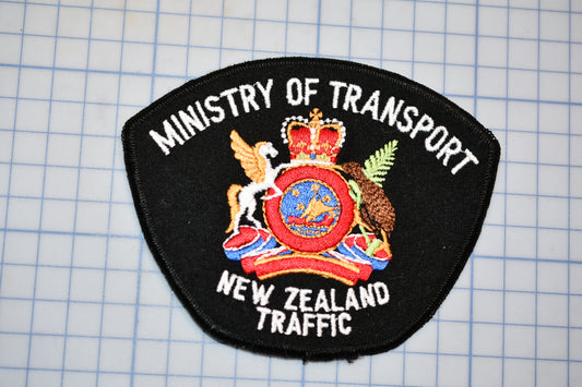 a black patch with the text "Ministry of Transport" and "New Zealand Traffic" written on it, along with a coat of arms.