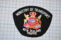 a black patch with the text "Ministry of Transport" and "New Zealand Traffic" written on it, along with a coat of arms.