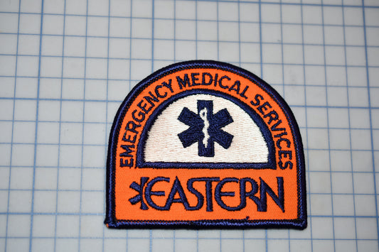 a patch with the text "EMERGENCY MEDICAL SERVICES" and a medical symbol, all set against a grid background.