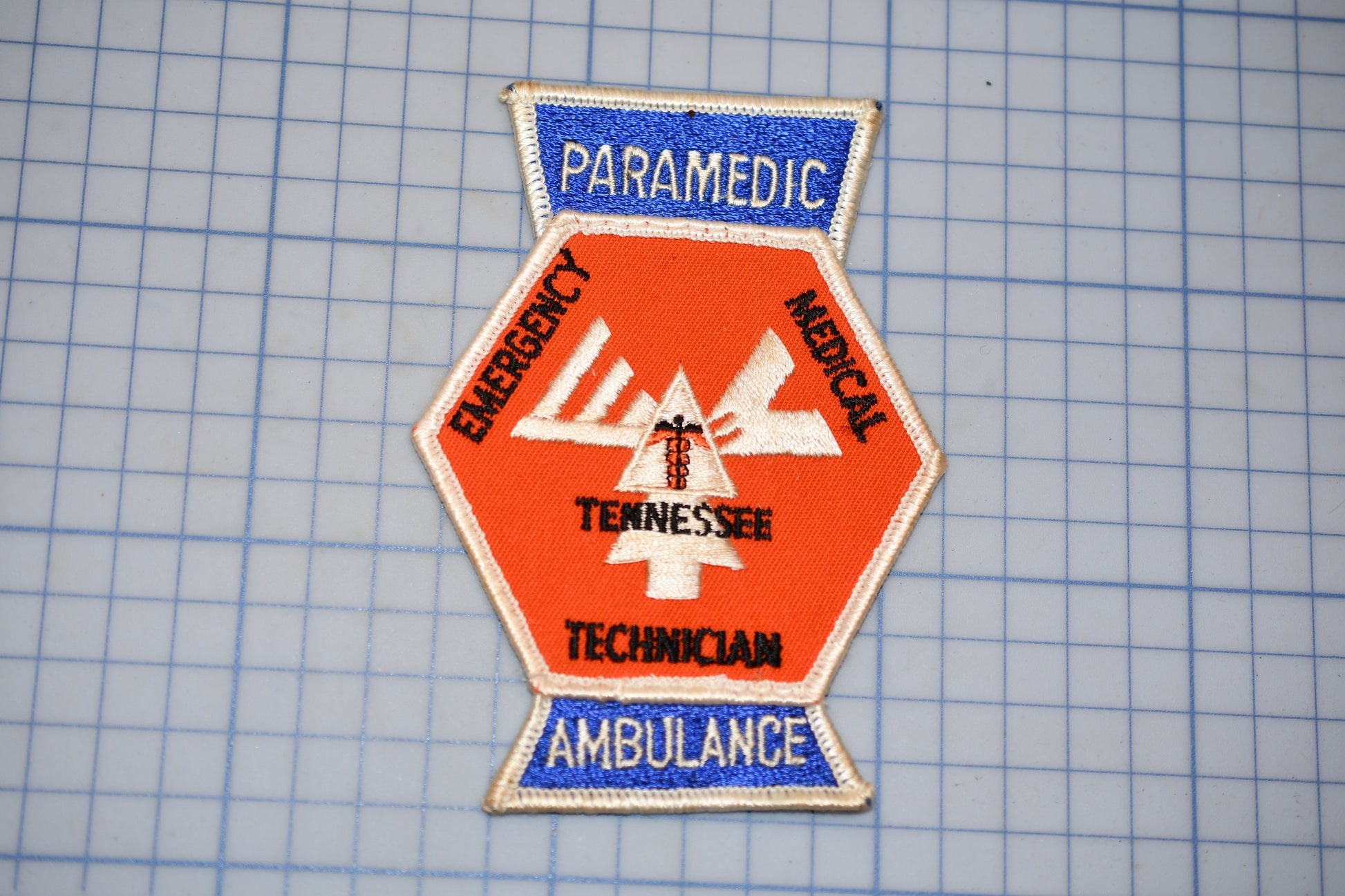 a patch with the words "PARAMEDIC", "EMERGENCY", "TENNESSEE", "TECHNICAL", and "AMBULANCE" printed on it, along with a medical symbol.