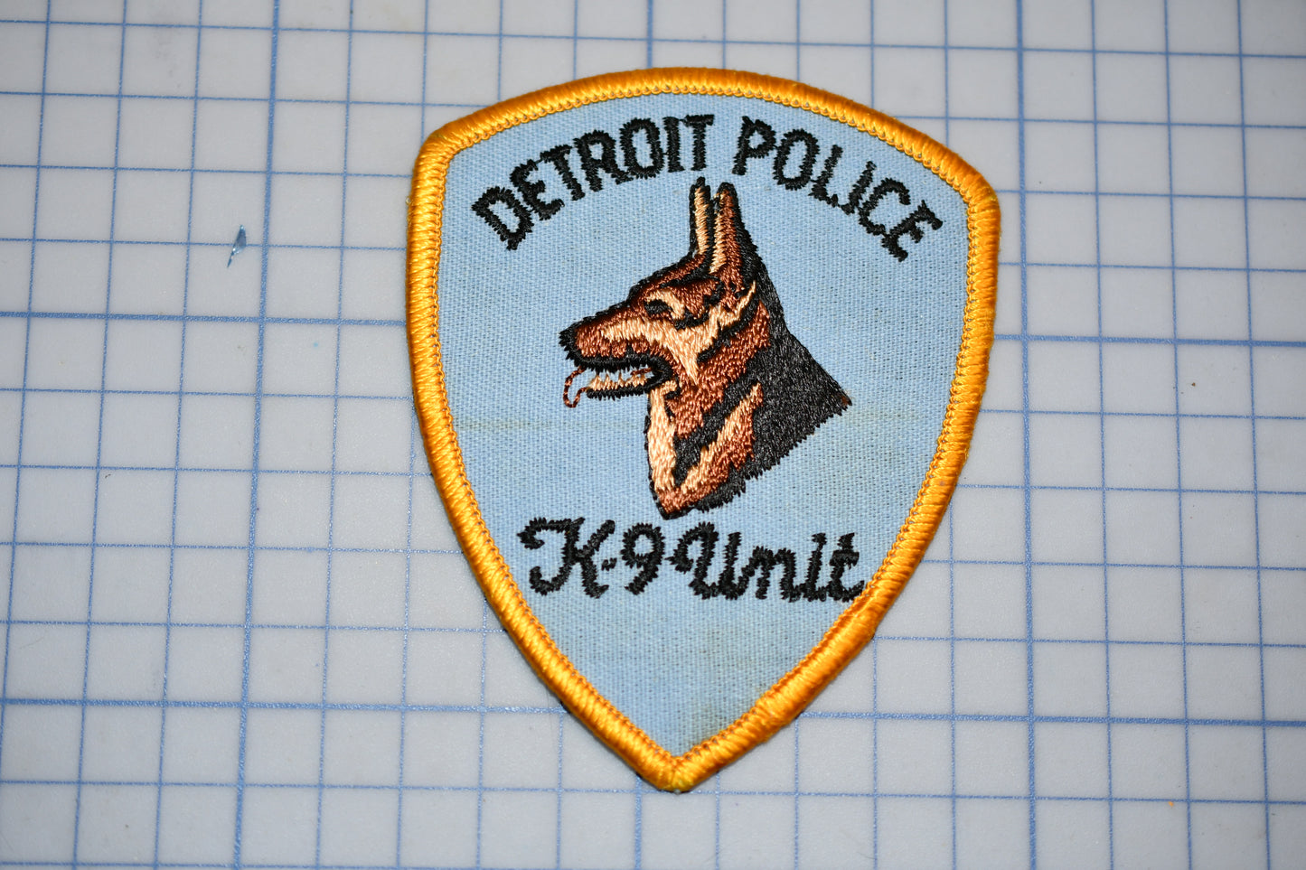 A Detroit Police K-9 Unit patch is displayed on a grid background.