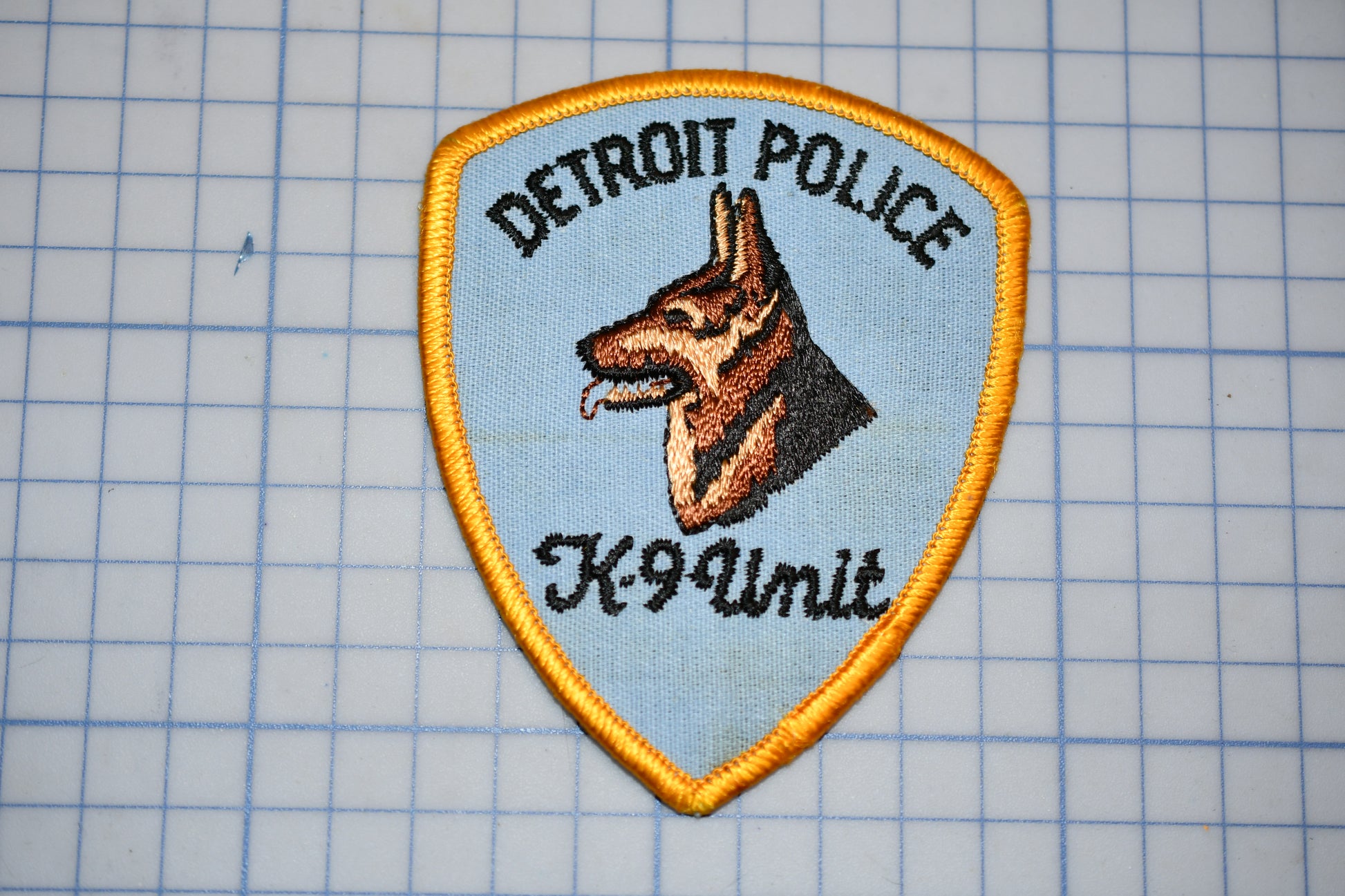 A Detroit Police K-9 Unit patch is displayed on a grid background.