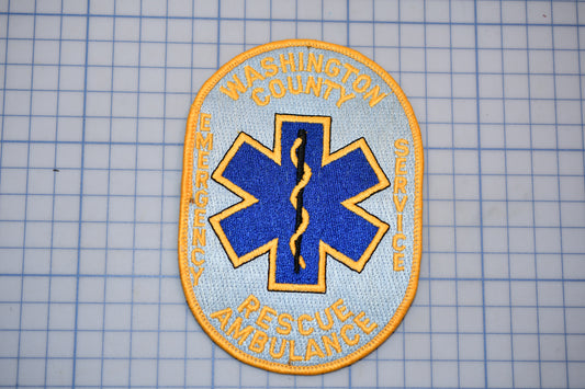 a patch with the text "WASHINGTON COUNTY EMERGENCY SERVICE RESCUE AMBULANCE" and a blue and yellow star-shaped symbol, which is commonly associated with emergency medical services.