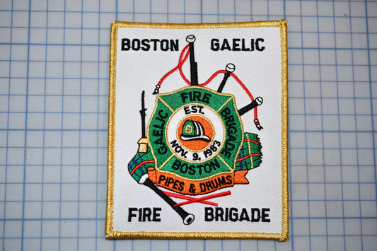 a patch with a fire department emblem, including a fire engine, a fire hose, and a fire helmet, along with the text "Fire Brigade" and "Pipes & Drums".