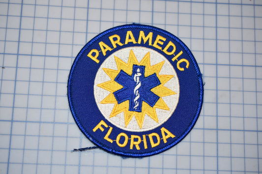 a blue and yellow patch with the text "PARAMEDIC FLORIDA" and a medical symbol, likely representing a medical emergency response team or organization.