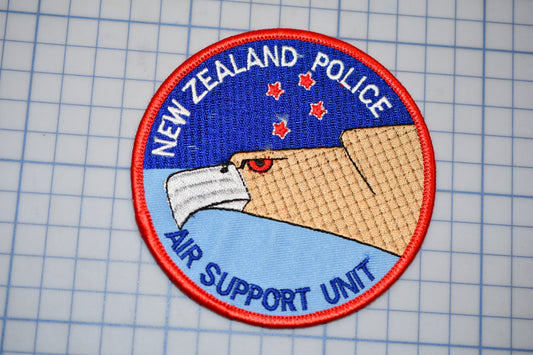 a circular patch with the text "NEW ZEALAND POLICE AIR SUPPORT UNIT" and an illustration of a bird of prey, likely a hawk, with a star on its head.