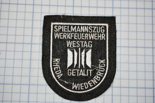 a black and white patch with text and symbols, placed on a grid background.